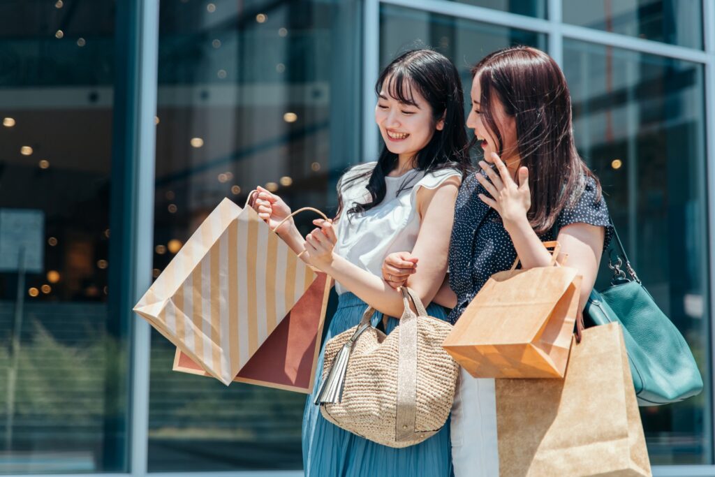 ショッピングバッグを手に楽しそうに笑う二人の日本人女性