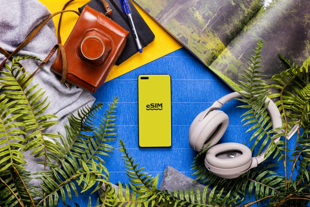 eSIM対応スマホと旅行グッズが並ぶフラットレイ構図のイメージ画像