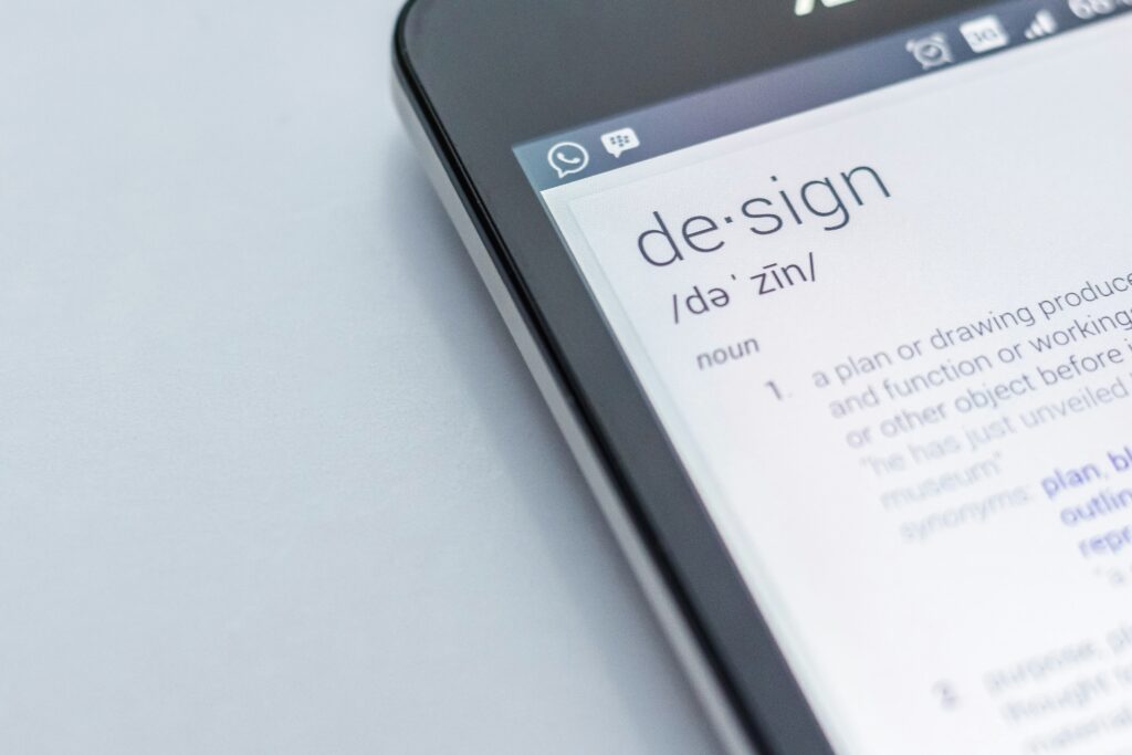 スマートフォン画面に表示された「design（デザイン）」という英単語とその定義。英語での申し込みや英語力を活かした手続きを象徴するイメージ