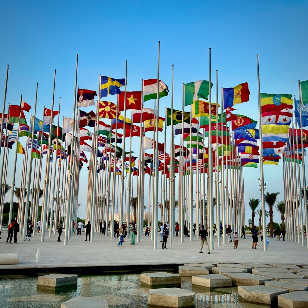 世界各国の国旗が立ち並ぶ広場、国際性や多言語対応を象徴するイメージ