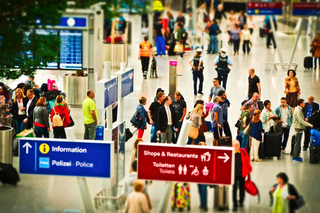 混雑した空港内で列をなす旅行者たち、セキュリティ通過の待ち時間を示すイメージ画像