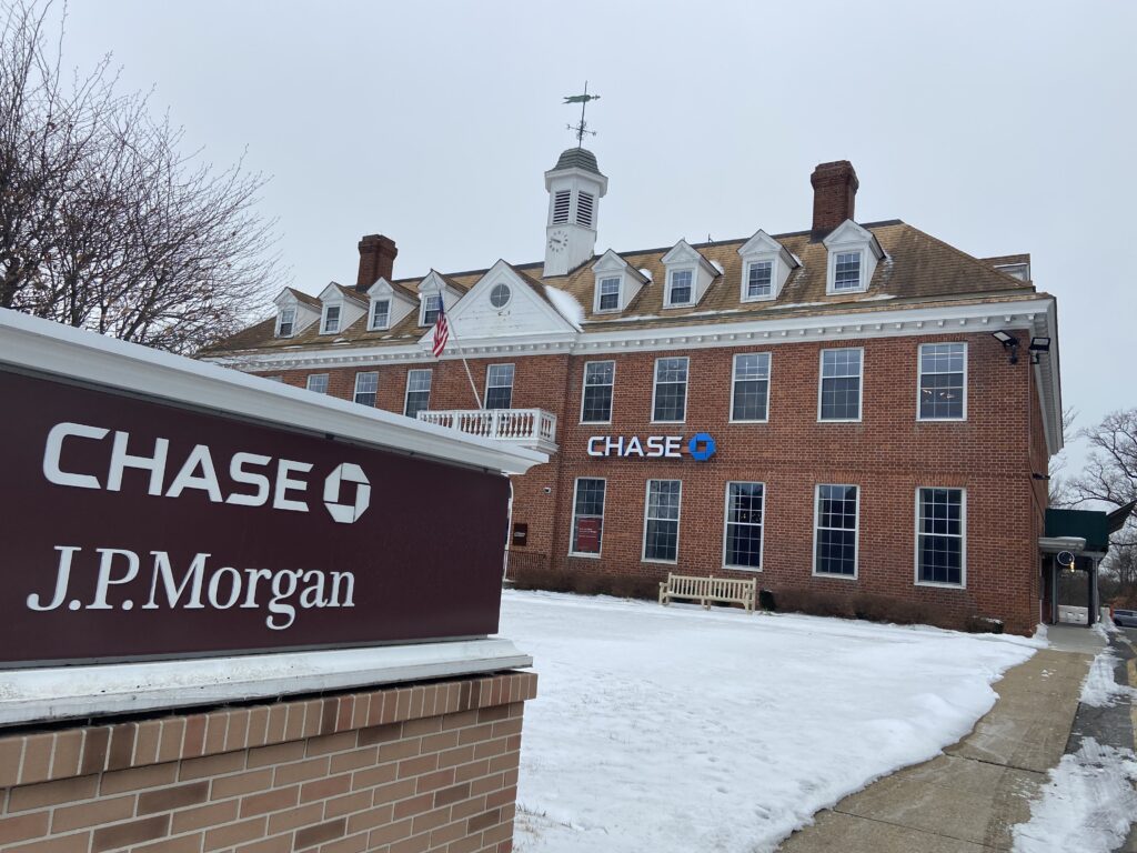 雪景色の中に建つ赤レンガ造りのChase Bank（チェース銀行）の支店と、手前に「J.P. Morgan」と書かれた看板が見える